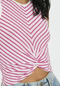 Top sans manches rayé rose et blanc avec un détail de nœud à l'avant, fabriqué en tissu texturé, présentant une coupe ajustée et un col rond.