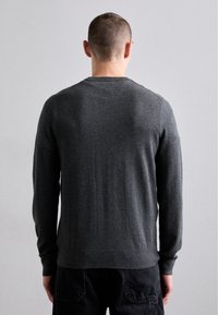 Mörkgrå stickad crewneck-tröja med långa ärmar, ribbade muddar och nederkant, slät textur, åtsittande siluett och utan framträdande mönster eller detaljer.