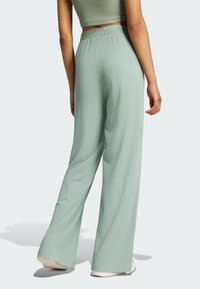 Jasnozielone, prążkowane spodnie typu wide-leg o luźnym kroju. Elastyczny pas i gładka faktura. Widoczne przeszycia i subtelny blask.