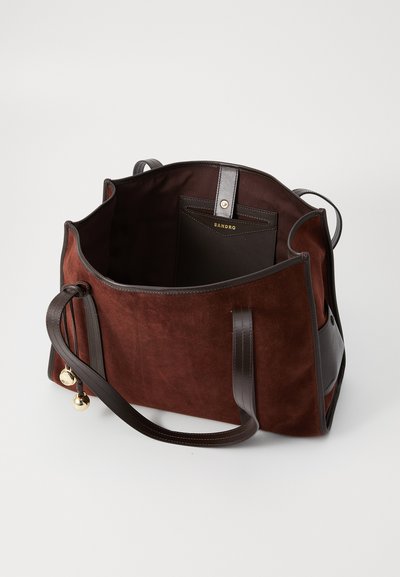 Sac tote en daim brun foncé avec des accents en cuir. Il présente un dessus ouvert, des poignées doubles et une poche intérieure avec une marque.