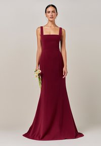 Bordo obleka do tal z kvadratnim izrezom in oprijetim trupom, izdelana iz gladkega blaga, z razširjeno krilce in minimalističnimi detajli.