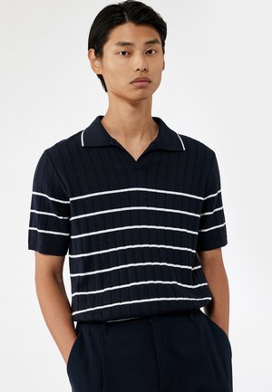 Polo de rayas en azul marino con mangas cortas, con líneas horizontales blancas, textura acanalada y un diseño de cuello clásico.