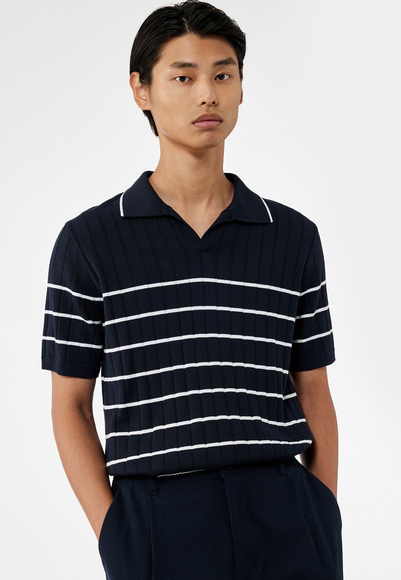 Marineblau gestreiftes Poloshirt mit kurzen Ärmeln, das weiße horizontale Linien, eine gerippte Struktur und ein klassisches Kragen-Design aufweist.