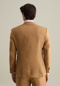 Giacca da suit su misura da uomo in lino marrone chiaro, design strutturato, revers a punta e spacchetto singolo sul retro. Texture sottile visibile.