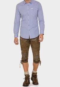 Chemise à carreaux bleue et blanche avec boutons, lederhosen en cuir marron avec broderie florale, longueur genou, assorti à des bottes marron à lacets.