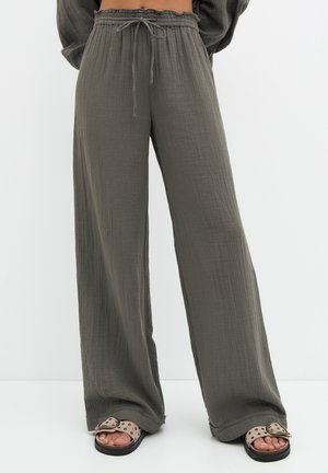 Lekkie spodnie o szerokich nogawkach w kolorze oliwkowej zieleni, wykonane z teksturowanej tkaniny, z elastycznym pasem i sznurkiem do wiązania.