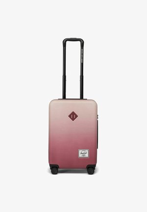 Valise Herschel avec un design ombragé dégradé, rose à blanc, coque rigide, poignée rétractable noire, quatre roues noires et un patch logo.