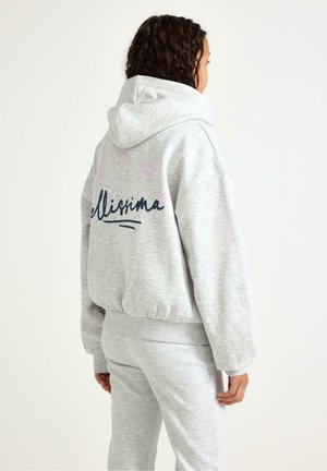 Harmaa huppari resoreilla hihoissa, jossa teksti "Bellissima" tummansinisellä ja vaaleanpunaiset tähdet yläpuolella, yhdistetty samansävyisiin alaosiin.