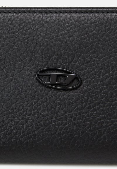 Portefeuille en cuir noir texturé mettant en avant un accent logo noir proéminent, avec des détails de couture visibles le long des bords.