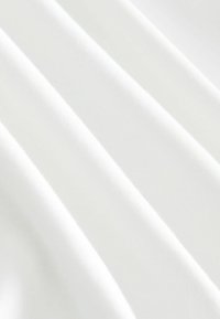 Weiße Stoff mit diagonalen Falten, die eine glatte Textur und subtile Schatten für Tiefe und Dimension zeigen.