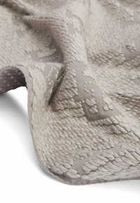 Light gray woven throw with textured patterns and raised accents. Features a soft, chunky knit design and a folded edge.