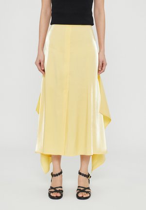 Yellow satin midi skirt with a high-low hem, featuring smooth texture and a subtle sheen. Paired with black strappy sandals.