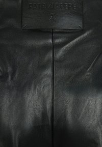 Borsa a mano rettangolare in pelle nera con superficie texturizzata, caratterizzata da un'etichetta con logo a rilievo. Finitura liscia, design minimalista.