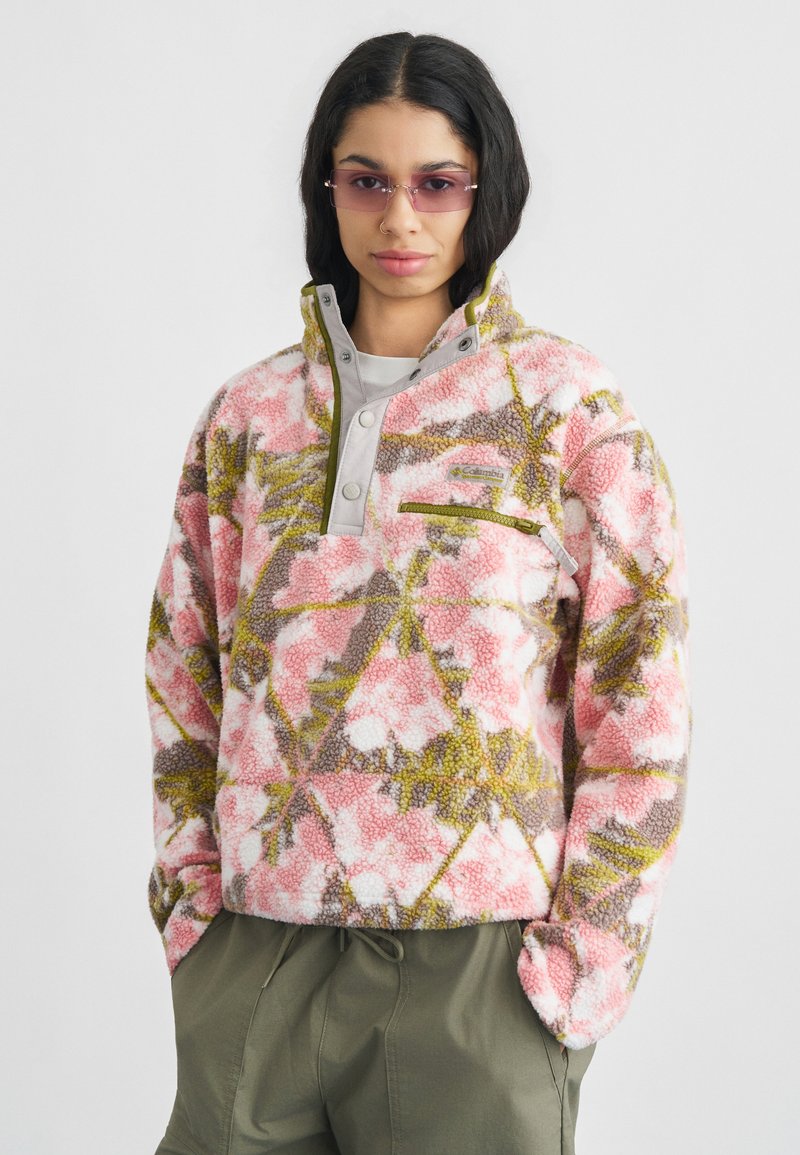 Φλις πουλόβερ σε ροζ, λευκό και πράσινο λουλουδάτο σχέδιο με κολάρο μισής ζ ip και τσέπη στο στήθος. Μαλακή υφή και χαλαρή εφαρμογή με πλαϊνές ραφές.