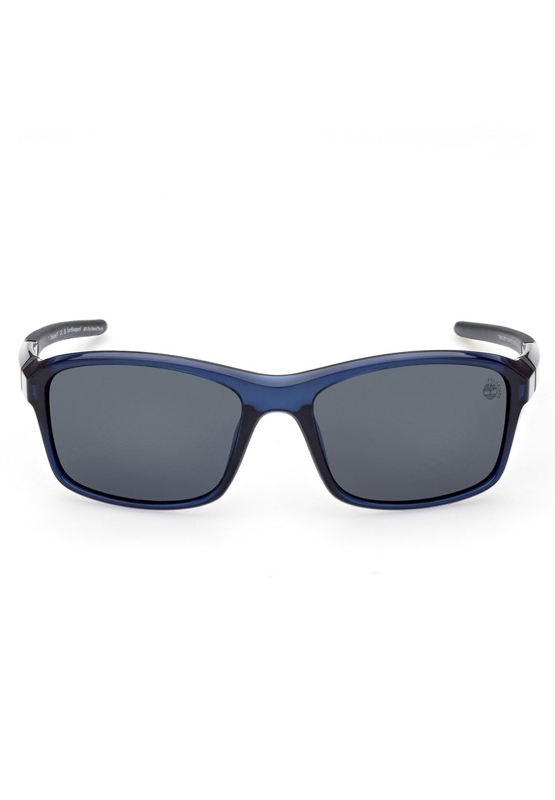 Gafas de sol con forma rectangular redondeada, lentes gris oscuro y montura de plástico azul marino con acentos metálicos en los laterales.
