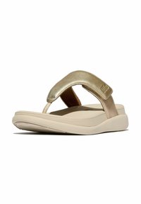 Sandali flip-flop dorati con una larga strap imbottita, soletta beige e suola in gomma leggera, caratterizzati da superfici lisce e un design minimalista.