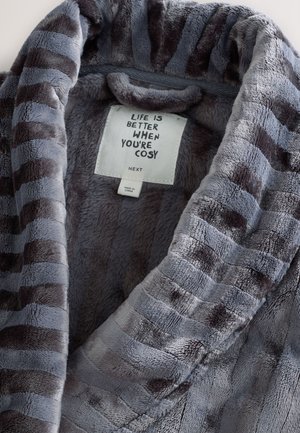 Albornoz de felpa gris con rayas gris oscuro. Textura suave, cuello chal y etiqueta con el texto "LA VIDA ES MEJOR CUANDO ESTÁS CÓMODO."