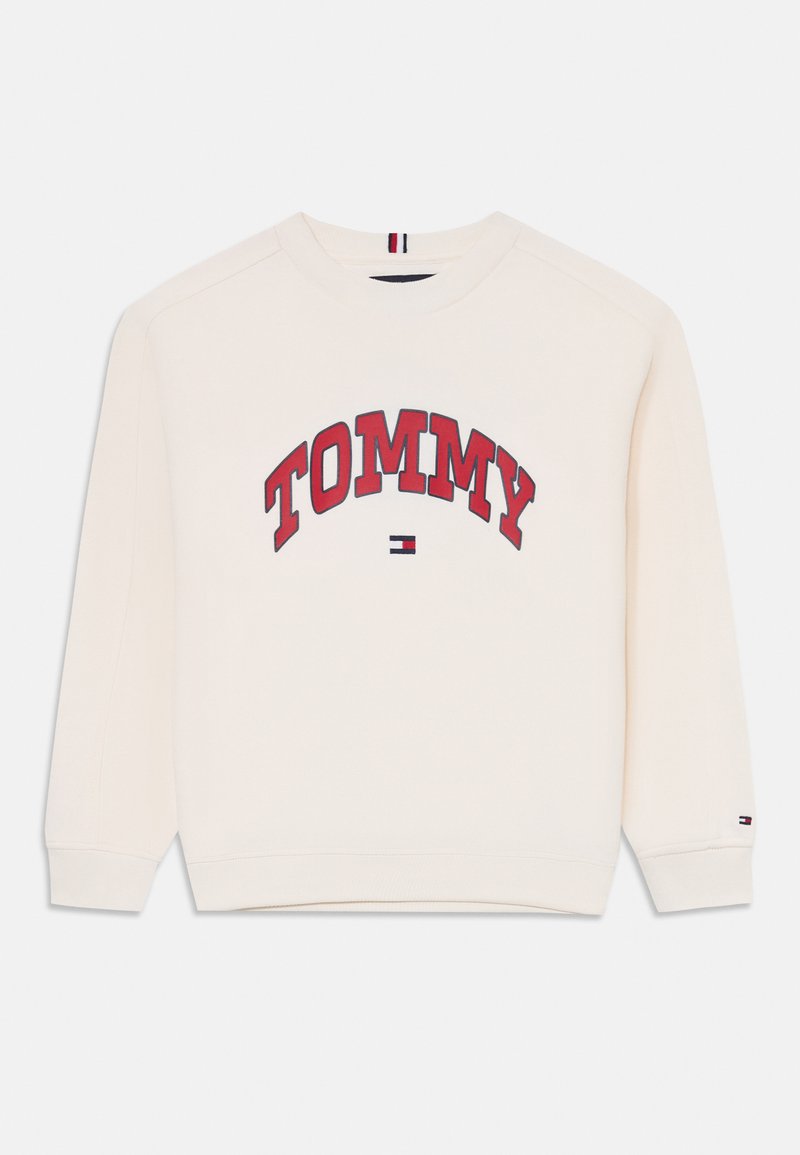 Kremgenser med rød "TOMMY" tekst, ribbestrikkede mansjetter, avrundet halslinning, og en liten marineblå, rød og hvit logodetalj på kanten.