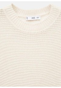 Kermanvärinen neulepaita, jossa on joustokaulus ja teksturoitu pinta, sekä pieni koko- ja alkuperätunnus kauluksessa.