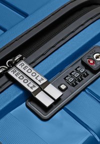 Valigia rigida blu con zip nera incisa "REDOLZ" bloccata con una serratura combinazione TSA nera a tre manopole.
