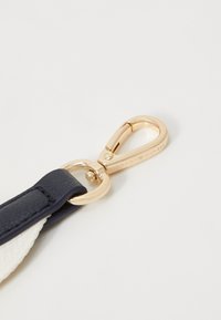 Bracelet en cuir bleu marine avec quincaillerie en métal doré, doté d'un fermoir à homard et d'une texture lisse, rehaussé de détails en tissu blanc.