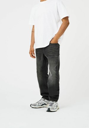 Sorte denim jeans med lige pasform, subtile falmede detaljer, parret med en plain hvid t-shirt og grå træningssko.
