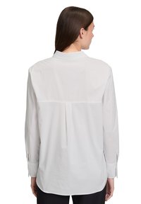 Witte overhemd met lange mouwen gezien vanuit de achterkant. Kenmerkt zich door een kraag, knoopsluiting bij de manchetten en een centrale plooi voor een ontspannen pasvorm. Glad, geweven textuur.