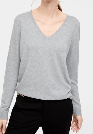 Pull gris à manches longues et col en V. Matériau en tricot doux avec une texture uniforme. Coupe décontractée avec des détails de couture subtils et un col légèrement relâché.