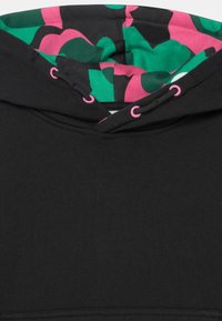 Černá mikina s kapucí, která má růžové a zelené vzorované podšívání v kapuci, doplněné růžovými průvlakami na stahovací šňůrku.