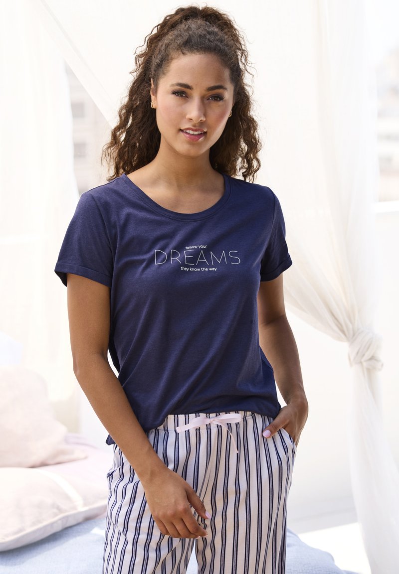 Navy blue t-shirt with short sleeves featuring white text: "follow your DREAMS they know the way." Worn with striped pajama pants.