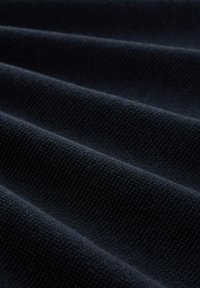 Donkerblauwe stof met een gestructureerd oppervlak, met een reeks gelijkmatig verdeelde plooien, die het zware gewicht en het weefpatroon benadrukken.