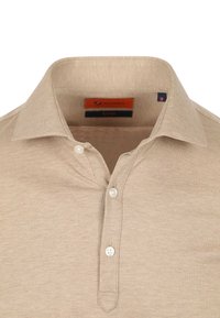 Beige poloshirt van een gestructureerde stof, met een kraag, een drukknoopsluiting met drie knopen en een label met maat M in de halslijn.