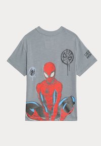 Camiseta de manga corta gris con un gran gráfico de Spider-Man en rojo con acentos azules, y diseños de arañas y telarañas en negro en el lado izquierdo.