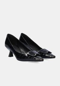 Zapatos de tacón puntiagudo negros hechos de cuero con patrón de cocodrilo, que cuentan con un pequeño lazo decorativo y un tacón bajo tipo bloque para mayor estabilidad.
