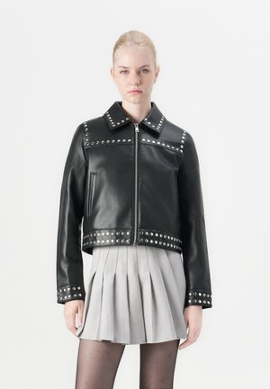 Veste en cuir noir avec des clous en métal argenté le long du col, des épaules et de l'ourlet. Design court avec un zip à l'avant et deux poches latérales.