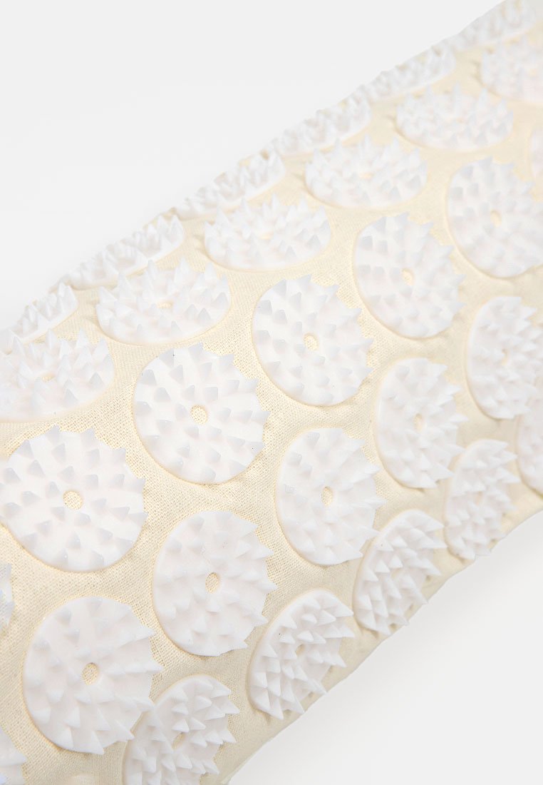 Rechteckige beige Stoffmatte mit gleichmäßig verteilten weißen runden Scheiben, die kurze, spitze Kunststoffspitzen für Massage oder Akupressur aufweisen.