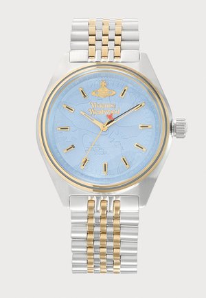Srebrna in zlata kovinska ročna ura s modrim številčnico, zlatimi urami in logotipom Vivienne Westwood na vrhu na sredini.