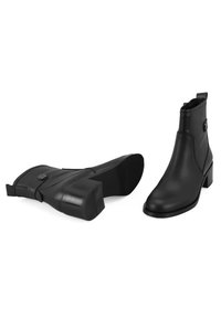 Bottines en cuir noir avec un talon carré, dotées d'une fermeture éclair sur le côté, de détails de sangle avec un bouton, et d'une semelle extérieure en caoutchouc texturé.