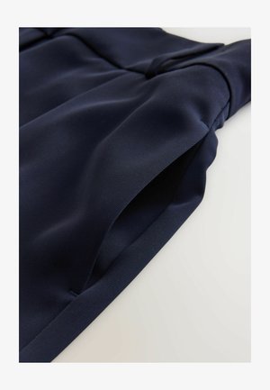 Tessuto blu navy con una texture liscia e una leggera lucentezza, con elementi di design piegati e cuciture visibili lungo i bordi.