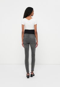 Gray skinny jeans with a high waist and black elastic waistband, worn with a fitted white t-shirt. Simple design, no visible patterns.
