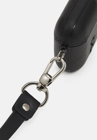 Carcasa din piele neagră cu o finisare texturată, având un clasp metalic argintiu și un sistem de prindere pentru curea, prezentând margini netede și o formă rotunjită.