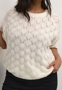 Flødefarvet strikket sweater med bladmotiv, korte ærmer, bred halsudskæring og blødt, tekstureret stof. Har en løs, afslappet pasform.