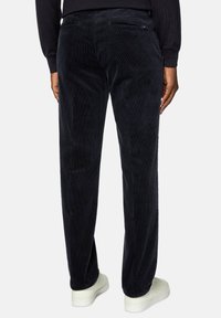 Marina kordbyxor med ribbad textur, två bakfickor med dragkedja, slim fit-design och elastisk midja, kombinerat med vita sneakers.