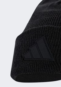 Černá pletená čepice se sklopeným lemem a matným černým trojúhelníkovým logem na boku.