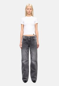 Witte getailleerde t-shirt gecombineerd met losse, vervaagde zwarte jeans. De jeans hebben een klassieke vijf-pocket ontwerp en een rechte pasvorm. Soepele stoftextuur.