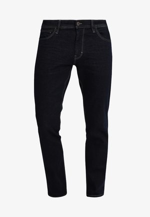 Temno modri kavbojke z klasičnim ravnim krojem. Imajo subtilne šive in sprednje zapiranje z gumbom.