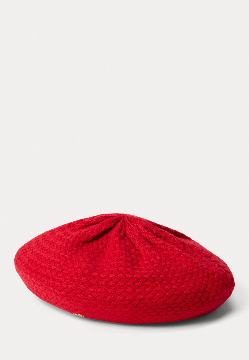 Beret vermelho trançado com forma arredondada e superfície texturizada. Apresenta um gathered central na parte superior e um pequeno destaque dourado ao lado.