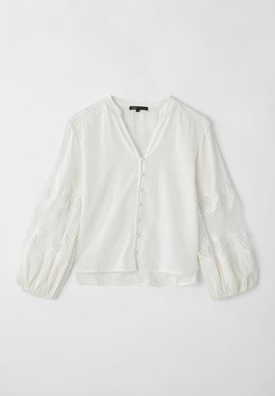 Vit blus med V-hals, knappstängning och genomskinliga, broderade långärmar som har ett vågigt mönster och texturerade detaljer.