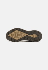 Suela de goma negra con patrón de textura en la banda de rodadura, presenta una entresuela beige y el logo de Timberland. Diseño duradero apto para uso al aire libre.