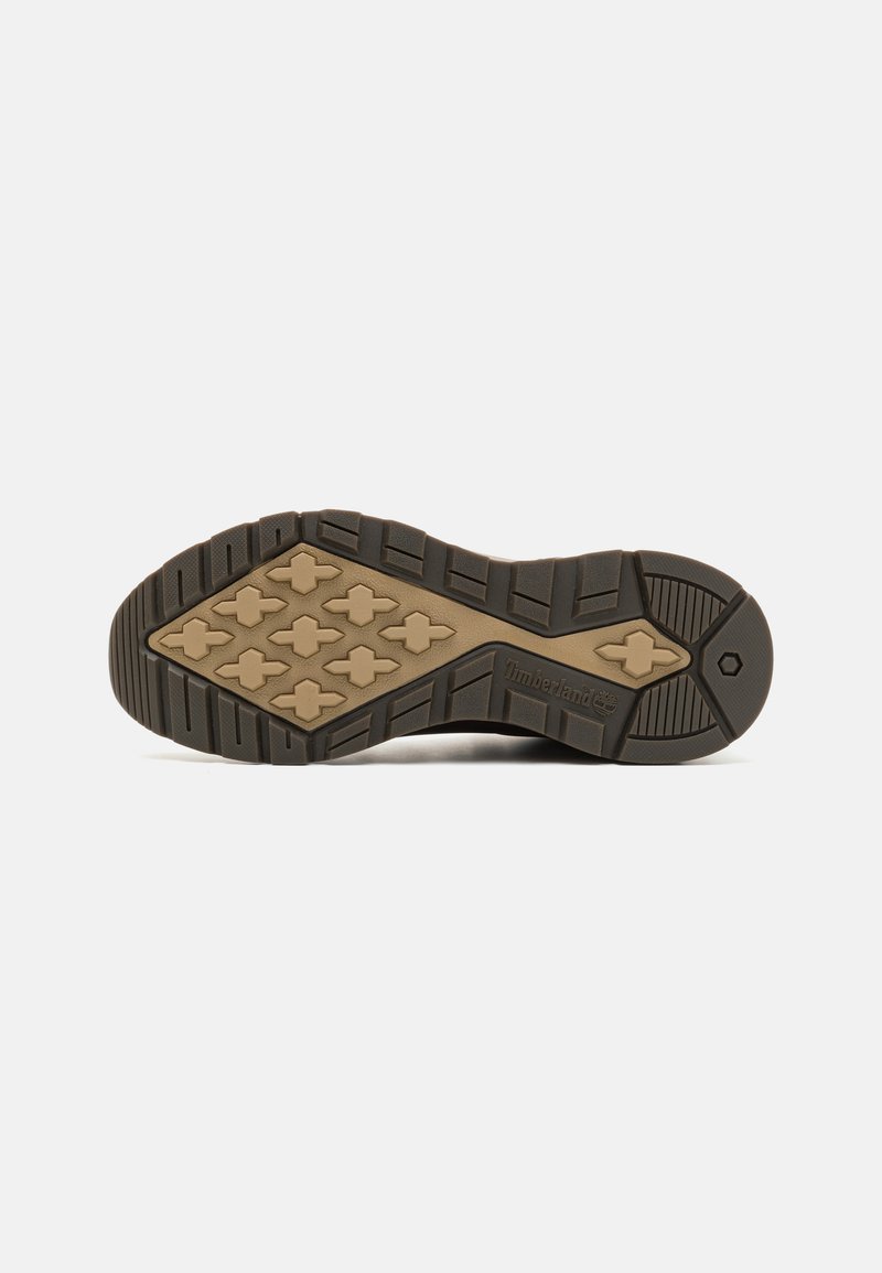 Czarna gumowa podeszwa z teksturowanym wzorem bieżnika, z beżową śródpodeszwą i logo Timberland. Wytrzymała konstrukcja odpowiednia do użytku na świeżym powietrzu.